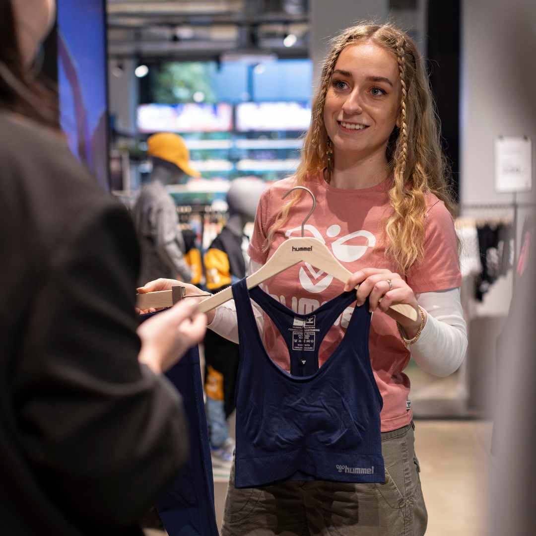 Glad hummel medarbejder fra Amager, vejleder kunde i at finde en sportsbh.